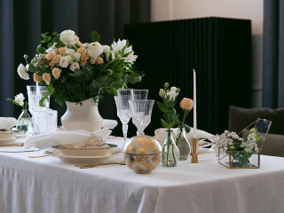 Virágokkal és üvegpoharakkal megterített elegáns asztal.