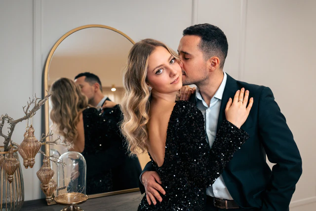 Elegáns pár egy tükör előtt, a férfi arcon csókolja a nőt