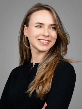 Smiling female headshot in a black top, turned slightly to the side against a grey background