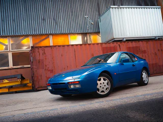 Kék Porsche 944 egy régi ipari épület előtt.