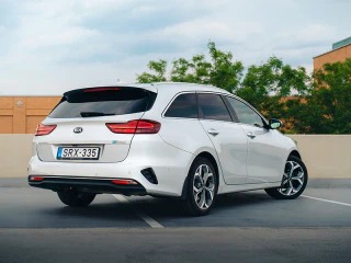 Fehér Kia Ceed kombi hátulnézetből egy szabadtéri parkolóban.
