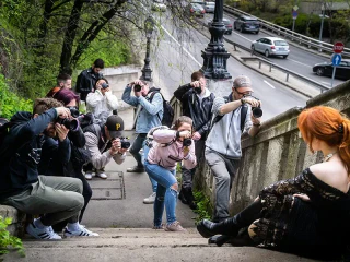 Fotósok egy lépcsőn ülő vörös hajú nőt fényképeznek.