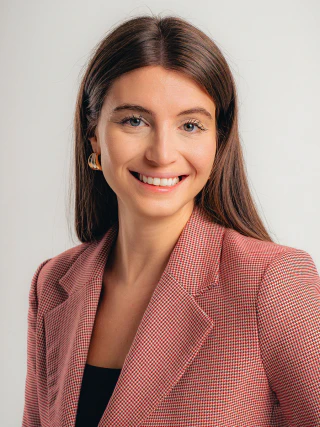 Smiling female business portrait in a pink blazer against a light background