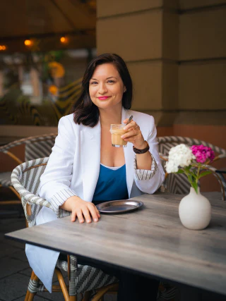 Portrait of a smiling woman holding a coffee at a café table