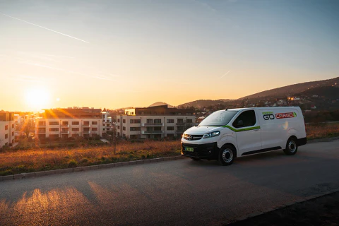 Fehér céges furgon naplementében egy út menti parkolóban.