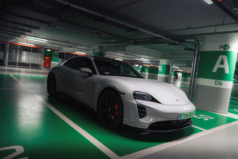 Szürke sportautó egy mélygarázs zöld parkolóhelyén.