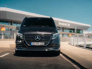Fekete Mercedes kisbusz a Liszt Ferenc Repülőtér Terminal 2A épülete előtt.