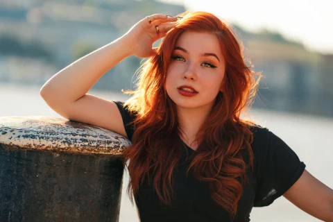 Portrait of a red-haired woman in a black top, photographed in warm sunset light