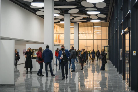 Vendégek beszélgetnek egy modern rendezvényhelyszín előterében.