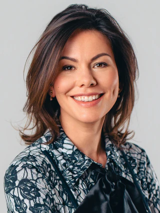 Smiling female portrait in a patterned blouse against a grey background