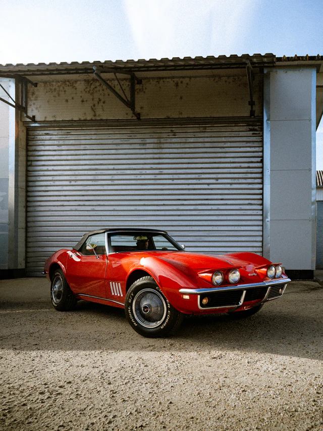 Piros Chevrolet Corvette egy ipari redőny előtt.