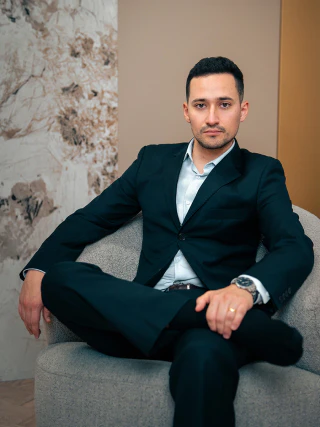 Elegáns öltönyt viselő férfi ülő portréja modern belső térben