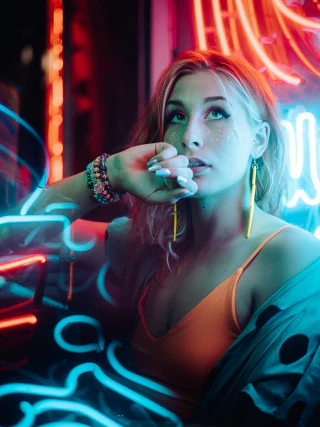 A woman in an orange top photographed under blue and red neon light