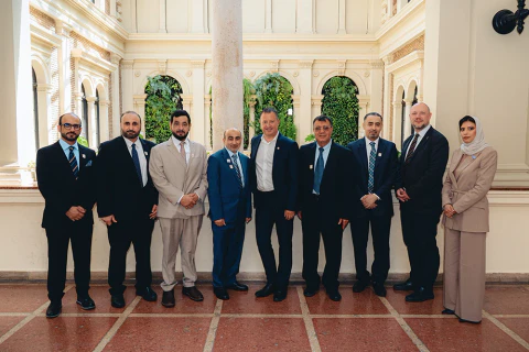 Elegáns ruhát viselő csoport áll egy díszes terem oszlopai között.