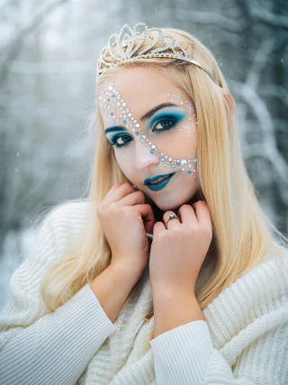 Winter portrait of a blonde woman wearing blue makeup and an ornate crown