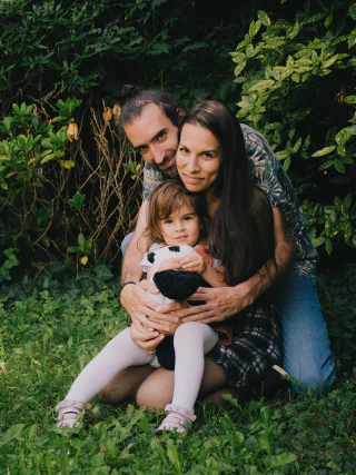 Parents sitting closely together on the grass with their young child