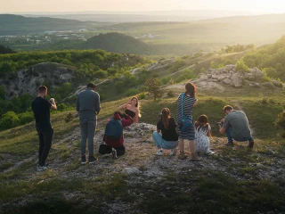 Fotósok egy nőt fényképeznek egy sziklás domboldalon naplementében.