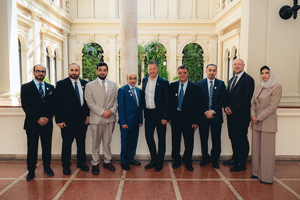Elegáns ruhát viselő csoport áll egy díszes terem oszlopai között.