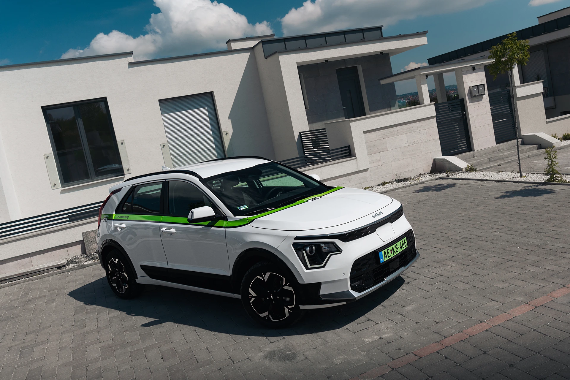 White Kia Niro company car in front of a modern family home.