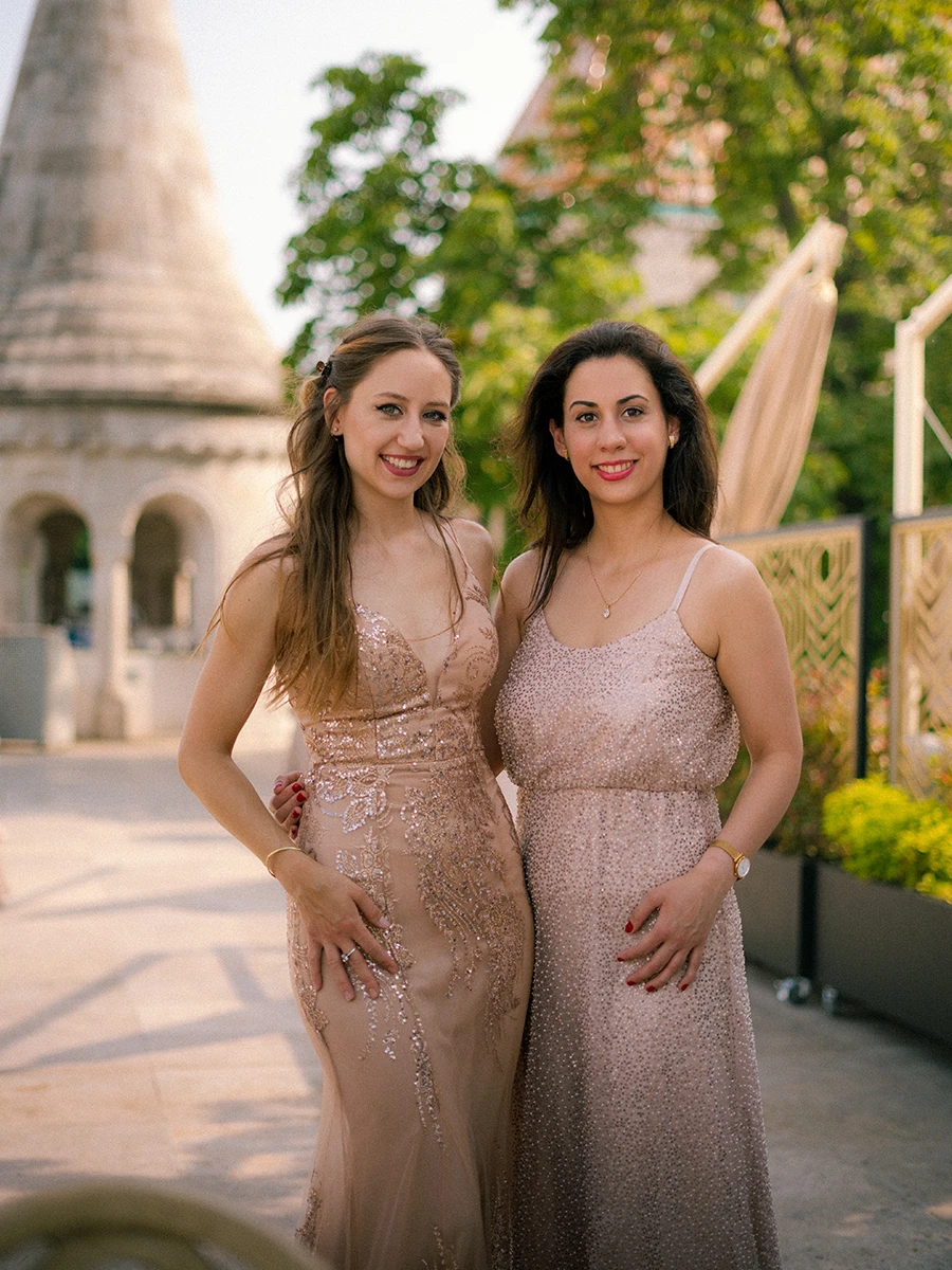 Two women wearing elegant sparkling dresses standing together in Budapest